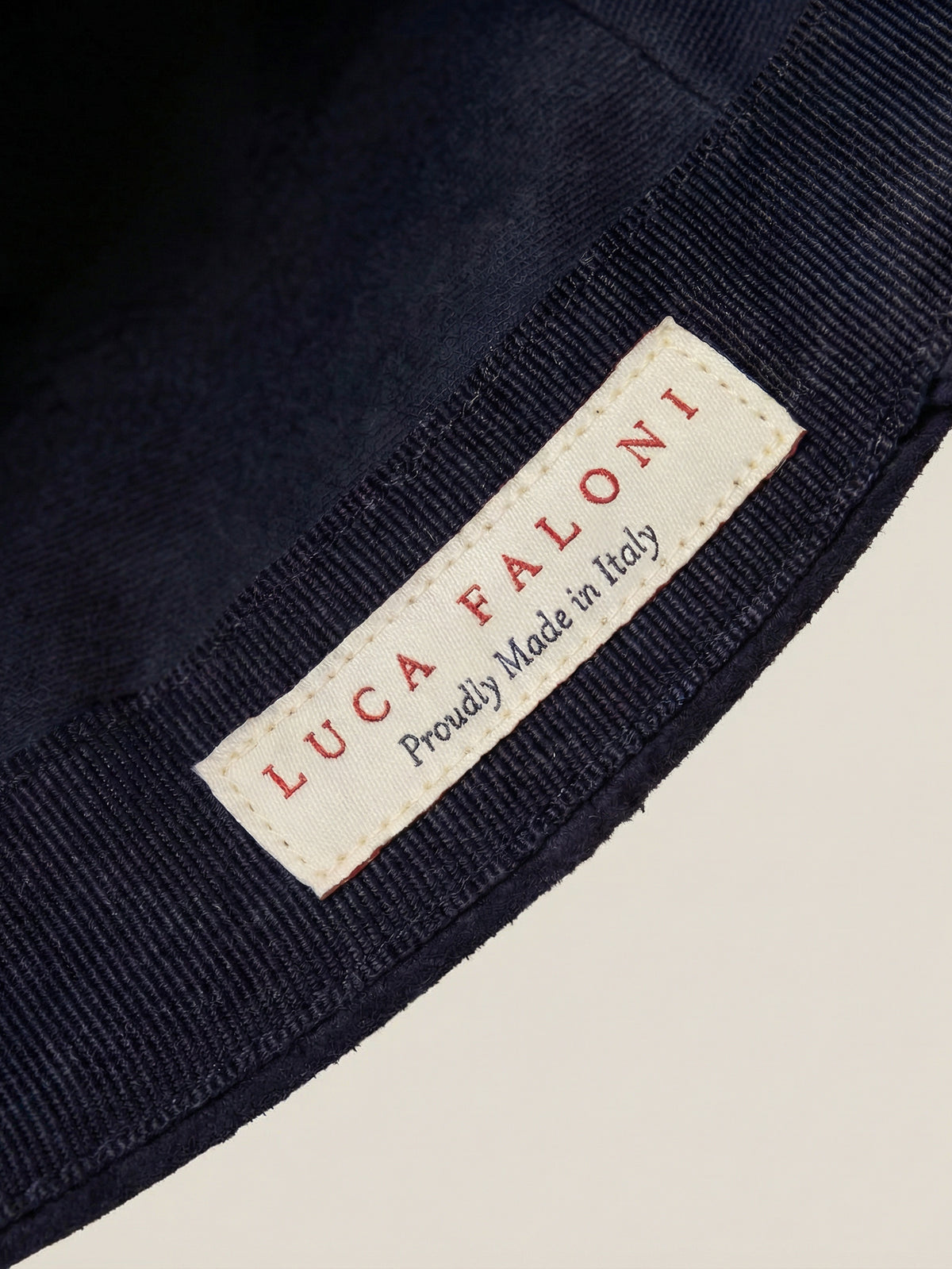 Detail view of the interior label on a midnight blue suede baseball cap, highlighting the Made in Italy craftsmanship.