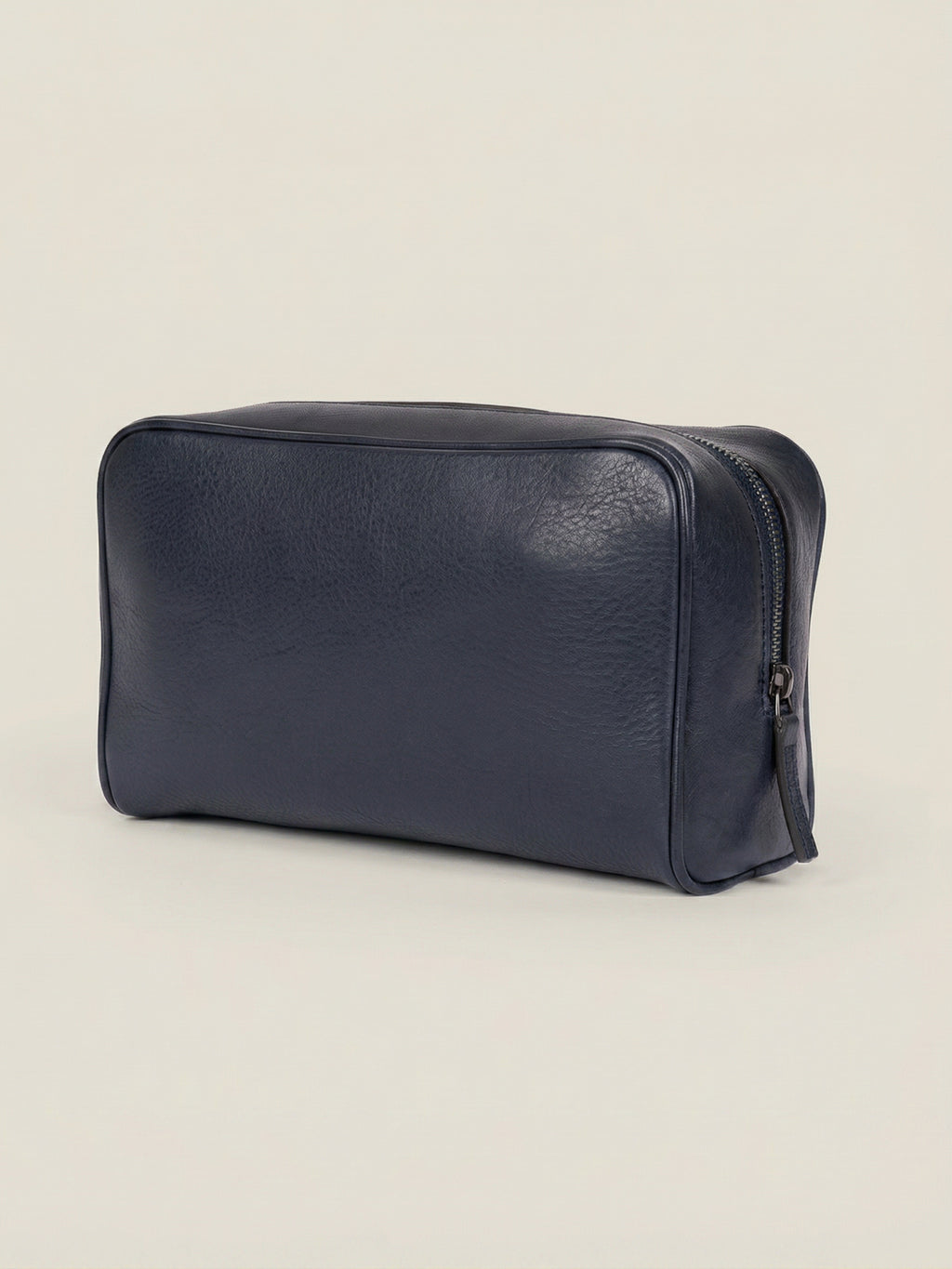 Three-quarter view of the Ink Blue leather wash bag in full-grain calfskin, set against a neutral background.