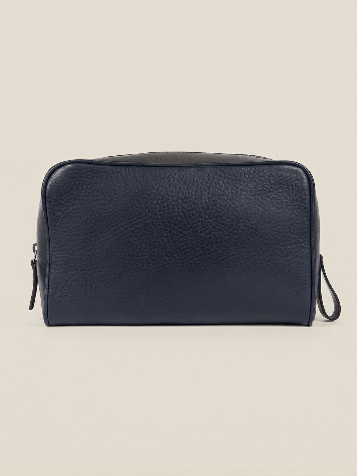 Front view of the ink blue leather travel wash bag, handcrafted in grained calfskin on a plain background.