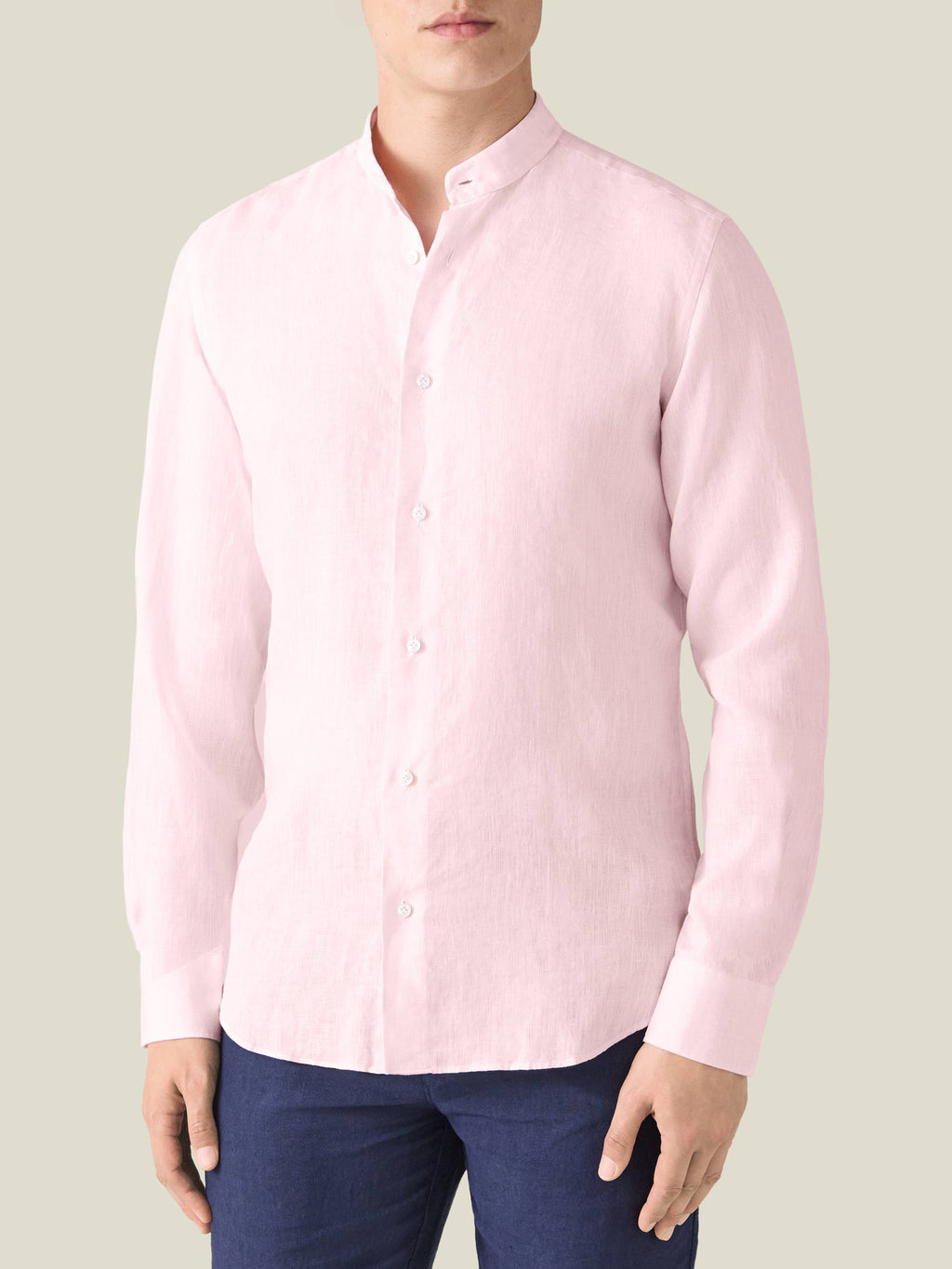 Light pink Versilia linen shirt with a band collar, worn by a model and paired with dark blue trousers.