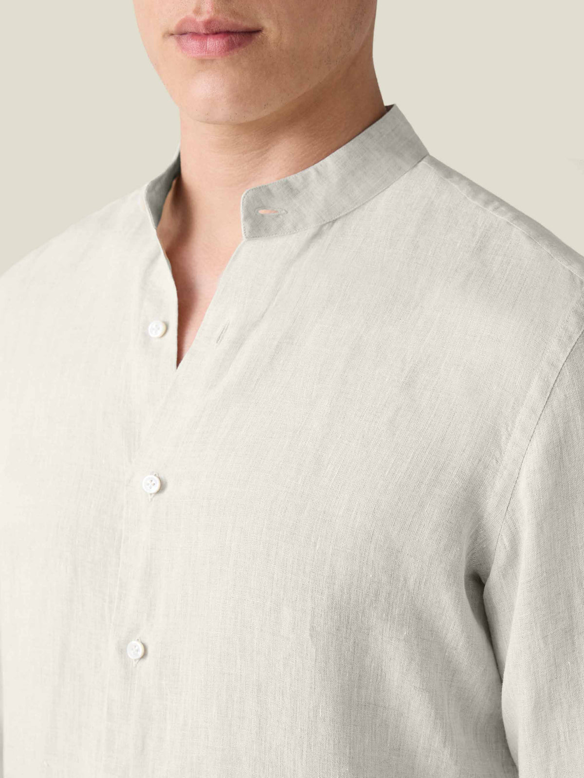 Close-up of the sand Versilia Linen Shirt featuring a band collar and mother of pearl buttons, worn by a model.