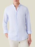Sky blue Versilia linen shirt featuring a band collar and mother-of-pearl buttons, worn by a model.