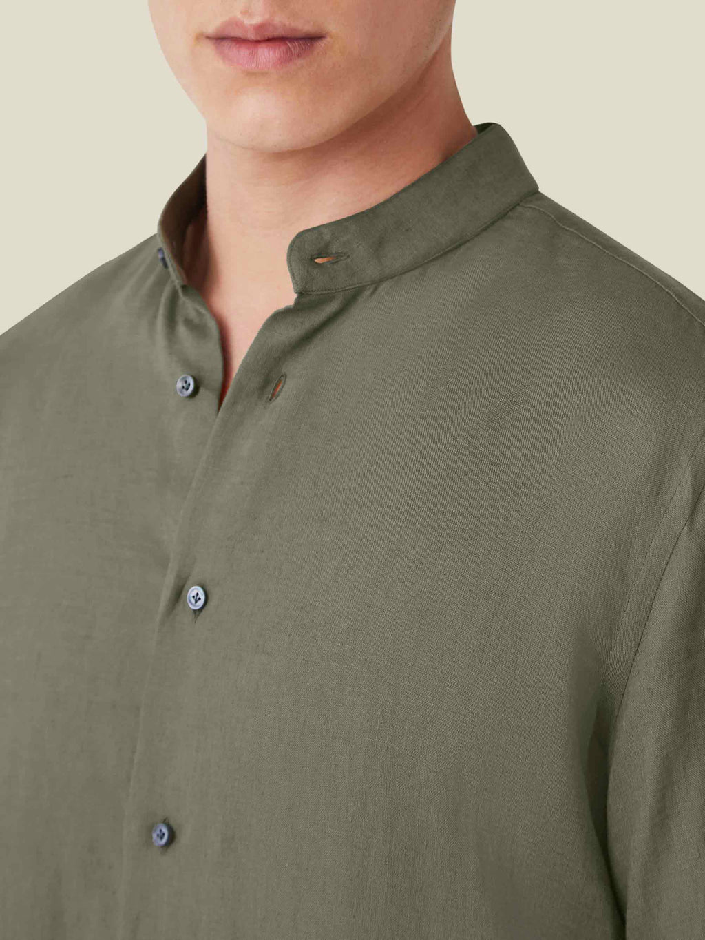 Close-up of the khaki green Versilia Linen Shirt featuring a band collar and mother of pearl buttons.