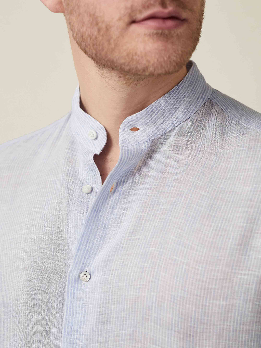 Close-up of the striped sky blue Versilia Linen Shirt with a band collar and mother-of-pearl buttons.