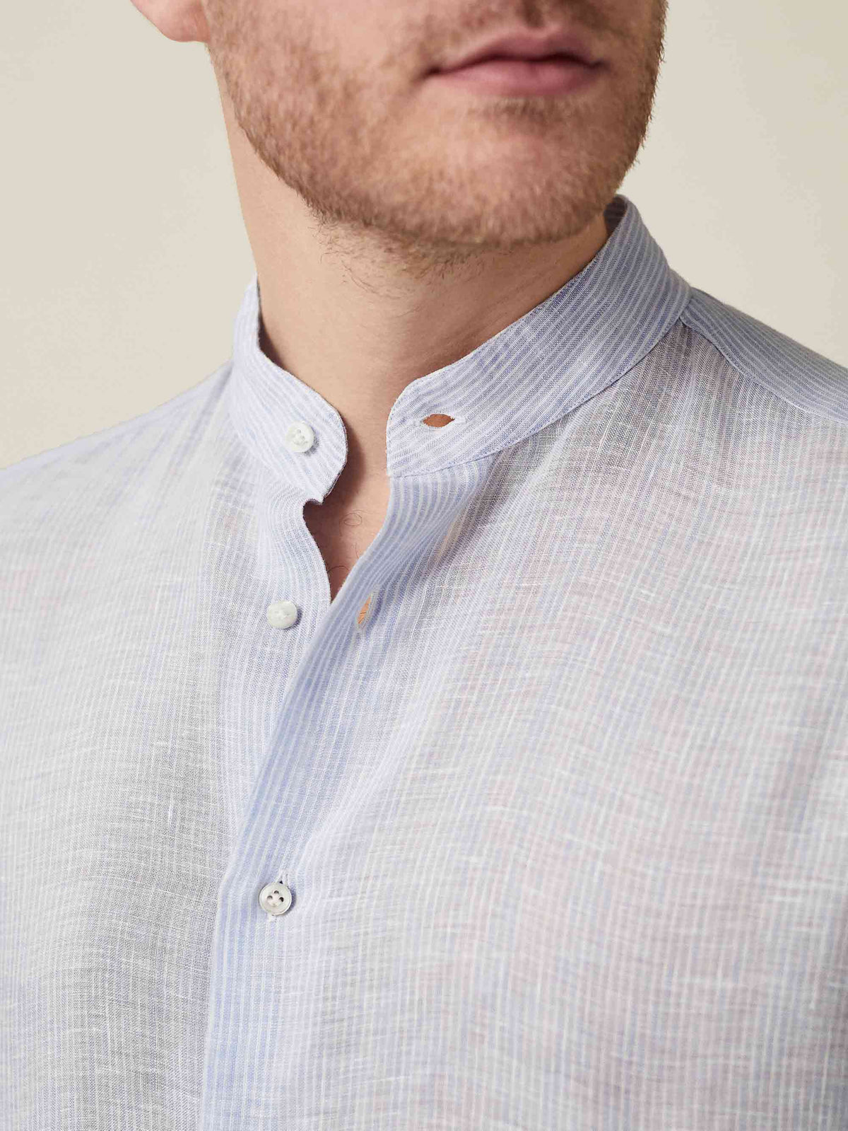 Close-up of the striped sky blue Versilia Linen Shirt with a band collar and mother-of-pearl buttons.