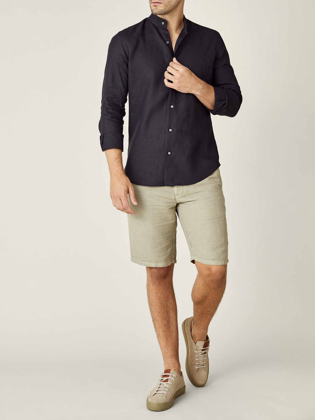Black band-collar Versilia linen shirt worn by a man with beige shorts, standing against a plain background.