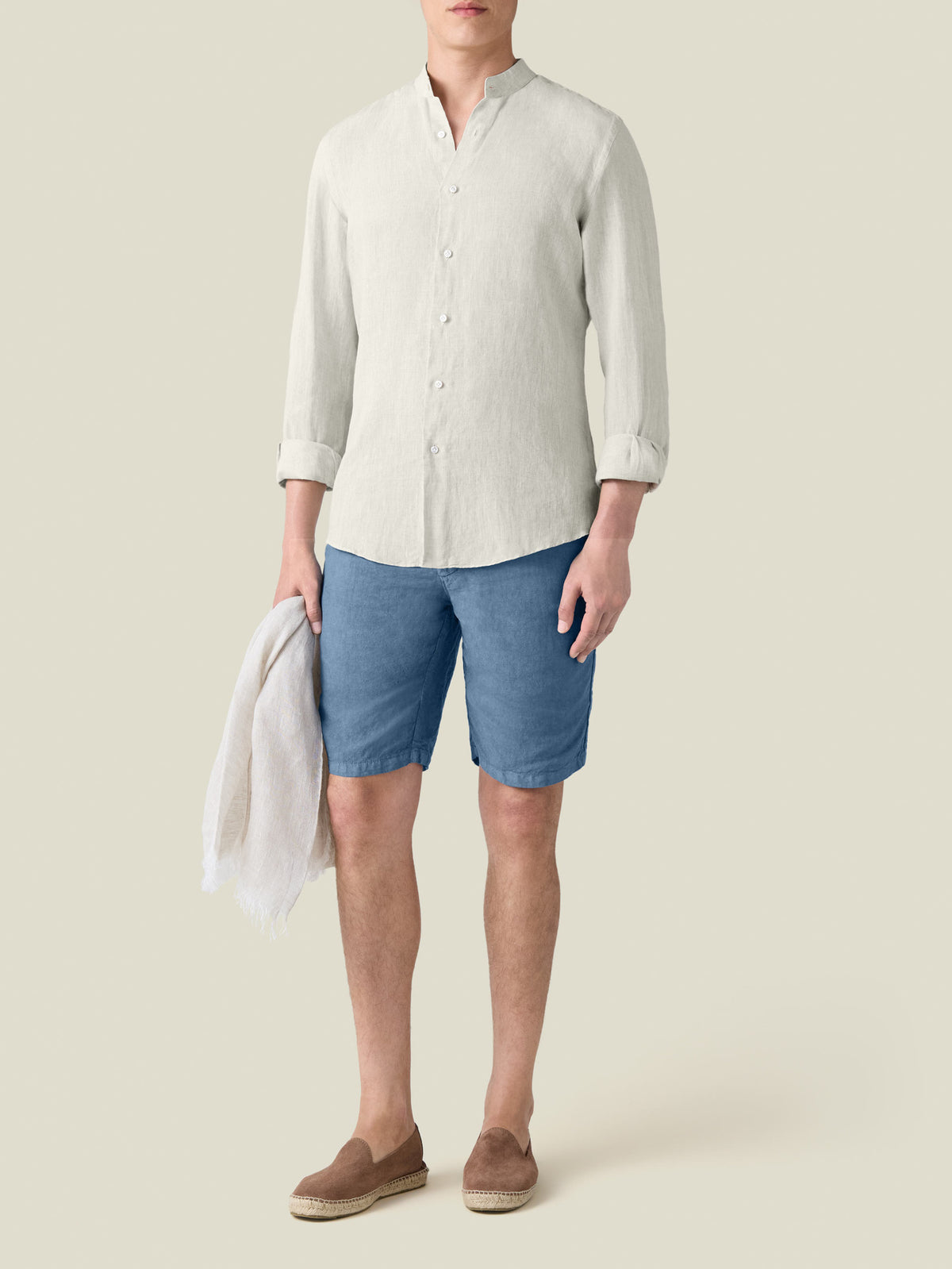 Front view of the sand Versilia Linen Shirt with a band collar, worn by a model with blue shorts and loafers.