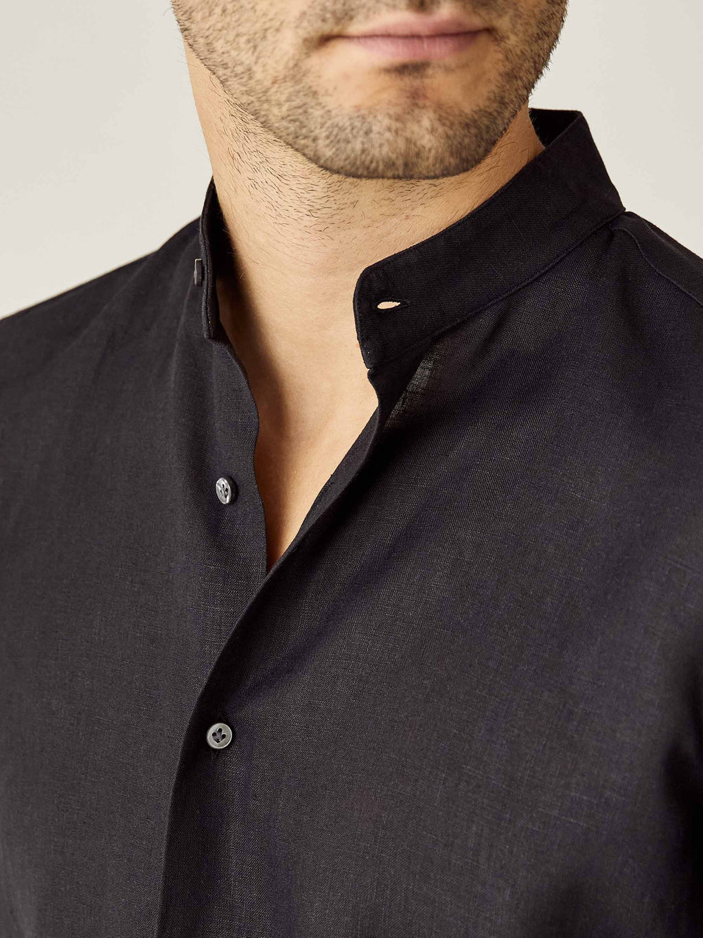 Close-up of the black Versilia Linen Shirt, highlighting the band collar and mother-of-pearl buttons.