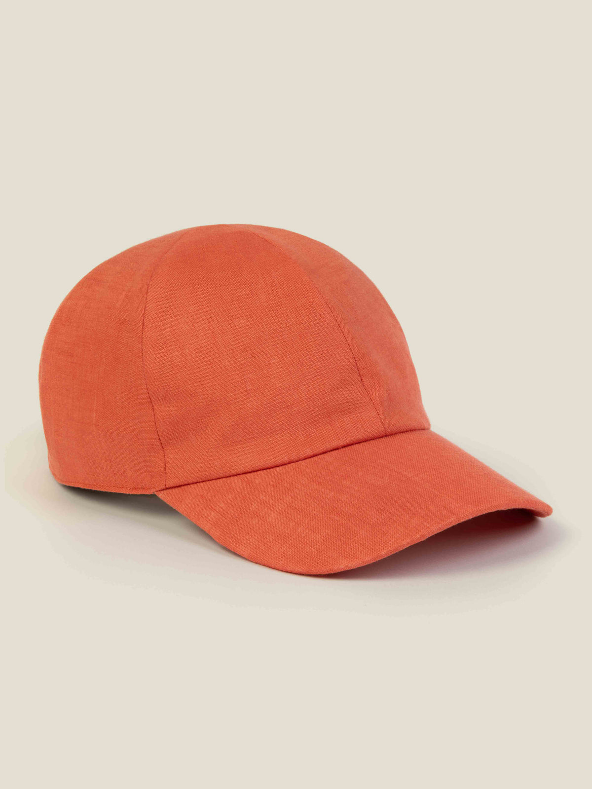 A side profile shot of the Luca Faloni Linen Baseball Cap in Coral, showcasing its classic shape and textured linen fabric.