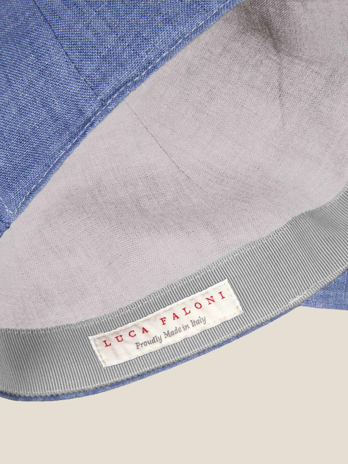 Close-up of the Chambray Blue Linen Baseball Cap, showcasing the interior 'Luca Faloni, Proudly Made in Italy' label.