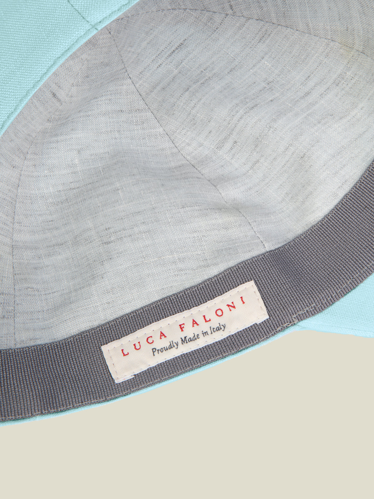 Detail shot of the Aquamarine Linen Baseball Cap, showing the contrasted inner lining and 'Proudly Made in Italy' label.