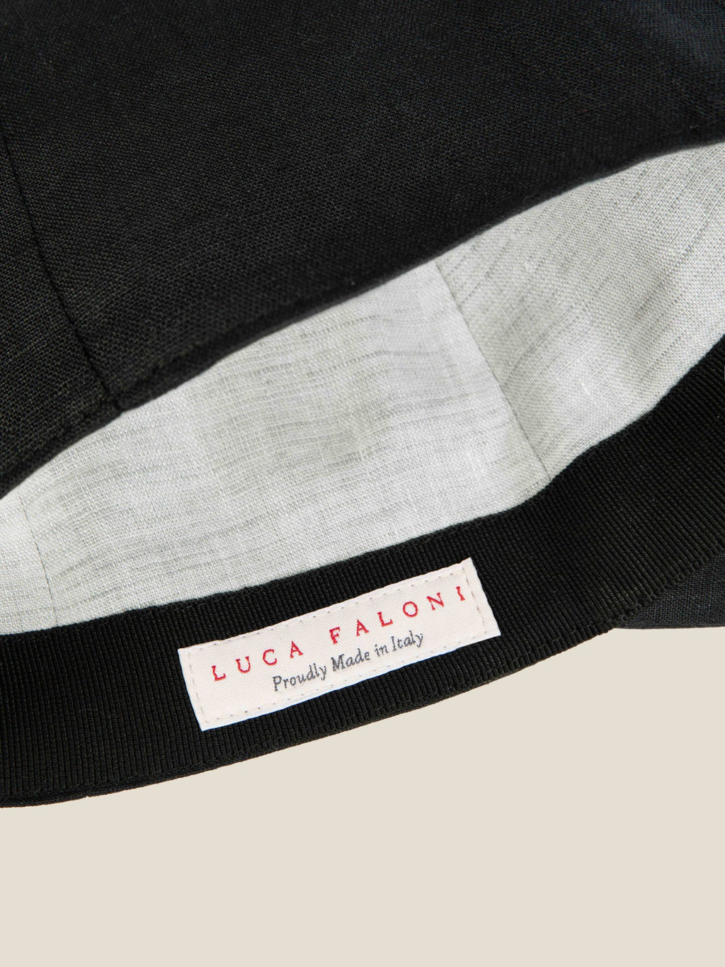 Detail of the Luca Faloni Black Linen Baseball Cap, showing the contrasted inner lining and 'Proudly Made in Italy' label.