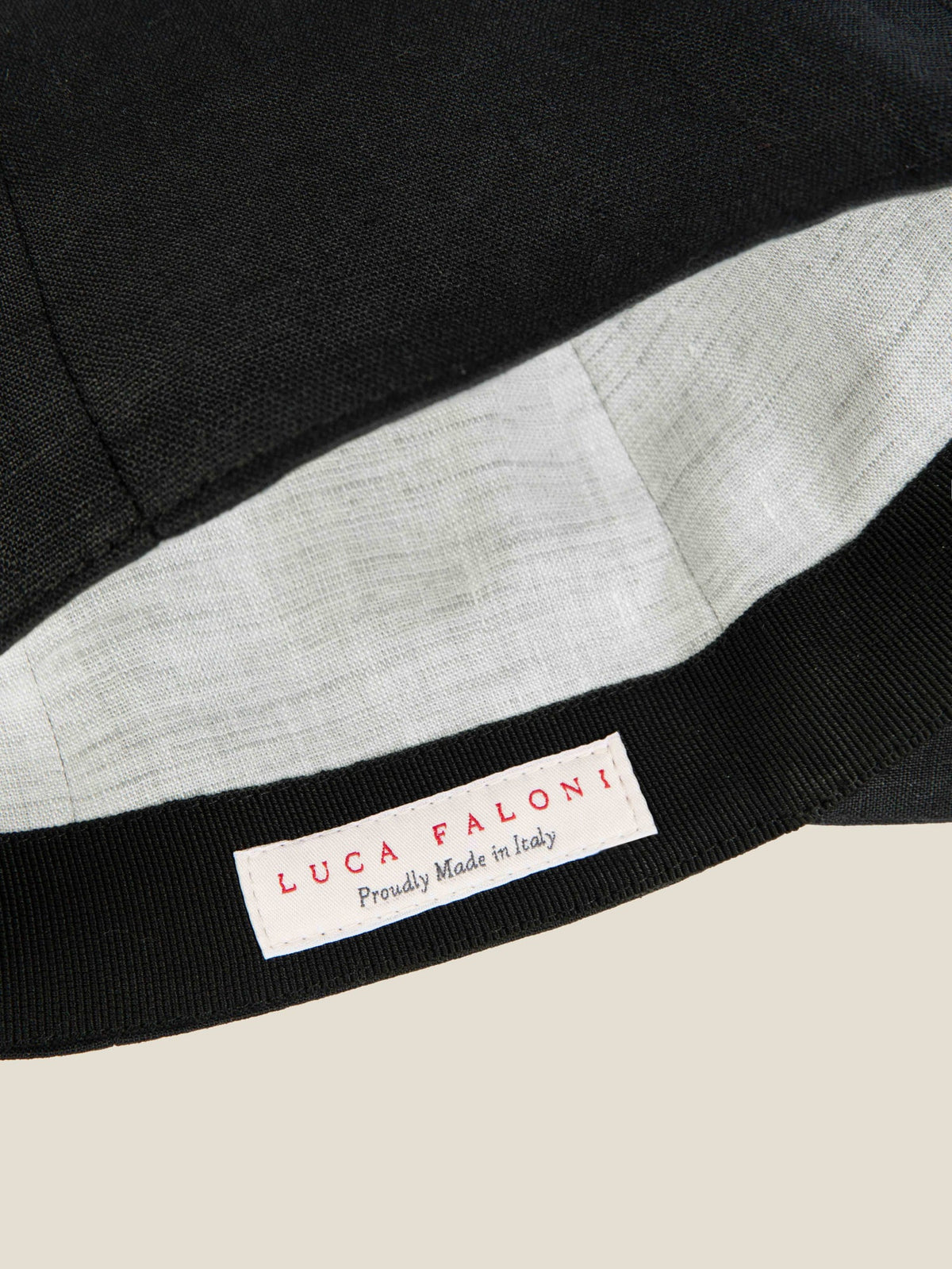 Detail of the Luca Faloni Black Linen Baseball Cap, showing the contrasted inner lining and 'Proudly Made in Italy' label.