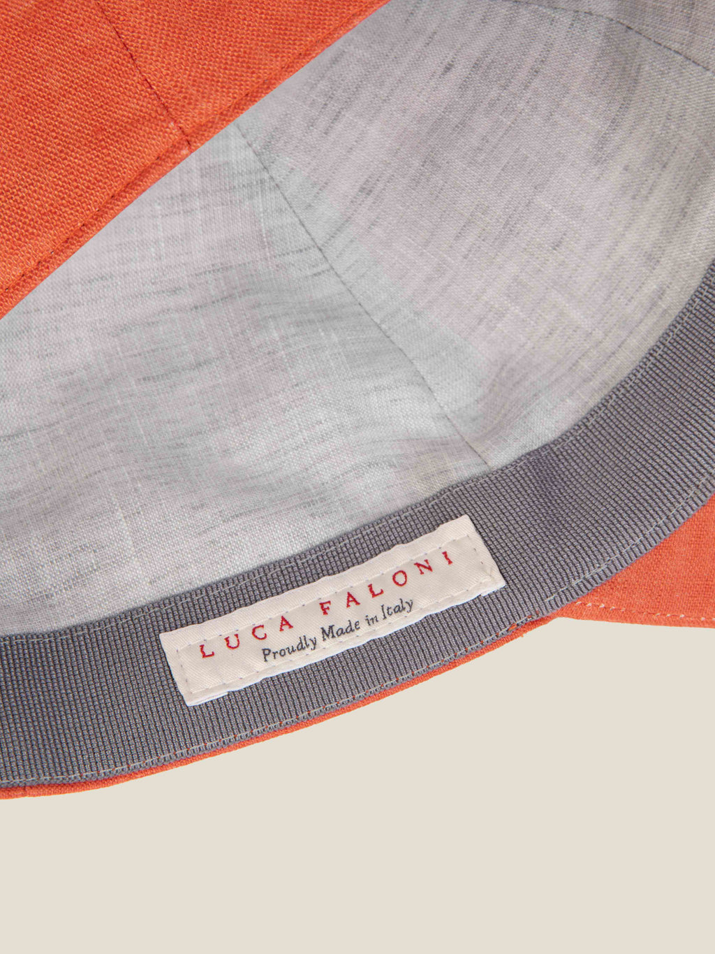 Close-up of the coral linen cap's interior, showing the 'Made in Italy' label and contrast lining.