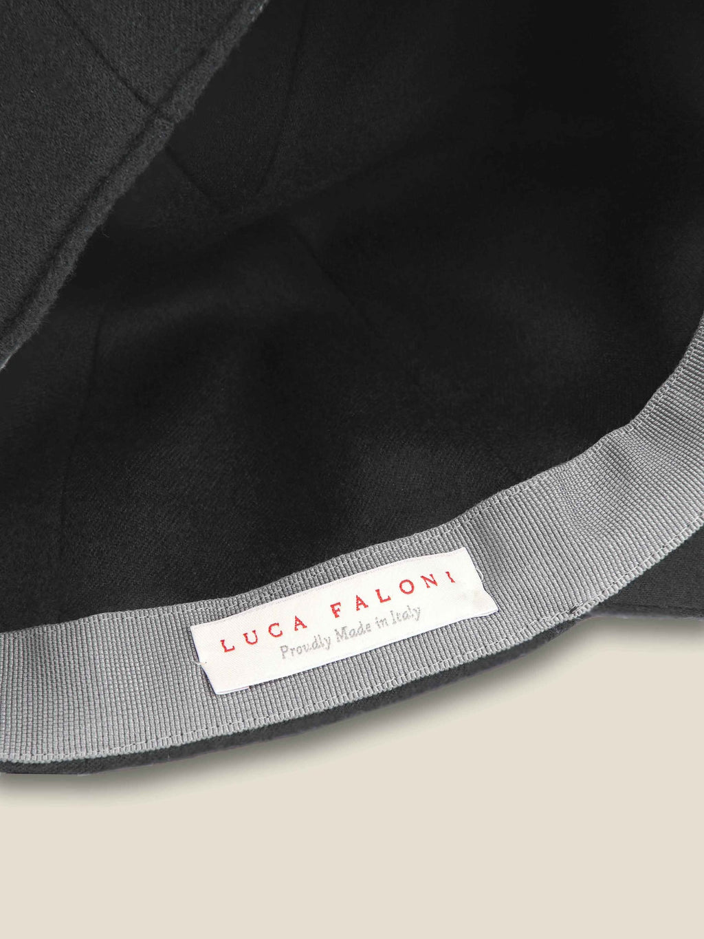 A close-up view of the charcoal grey cashmere baseball cap's interior, highlighting the Luca Faloni brand label.