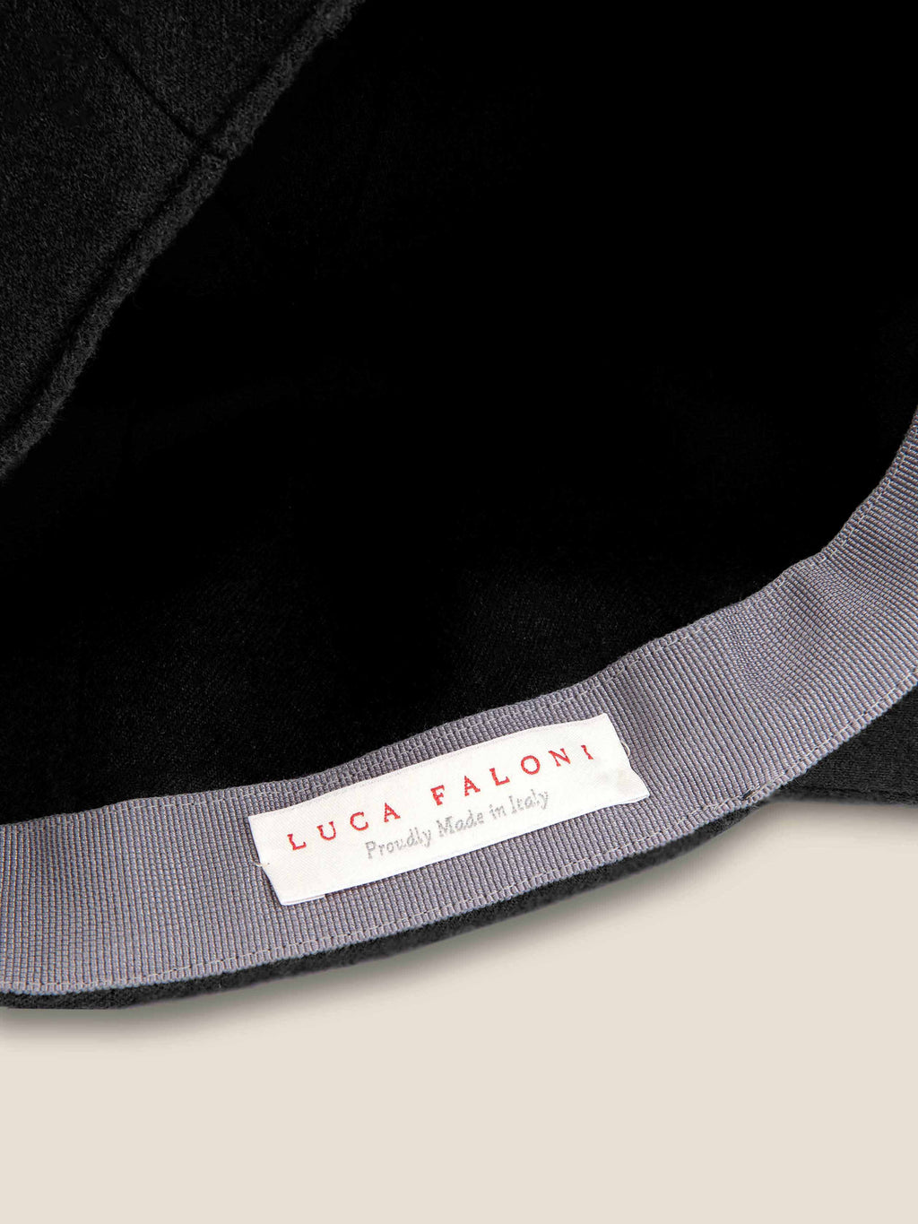 Close-up of the Luca Faloni label inside the black cashmere baseball cap, showcasing its 'Proudly Made in Italy' origin.