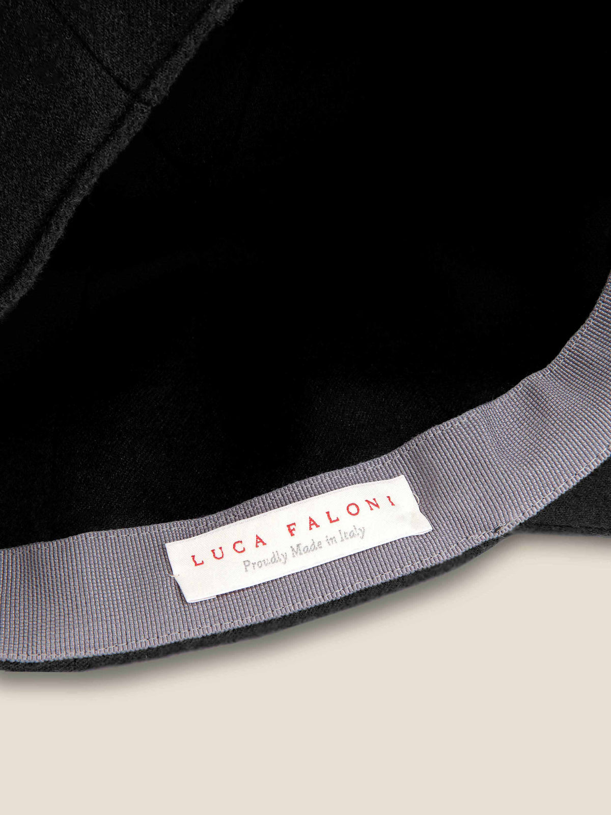 Close-up of the Luca Faloni label inside the black cashmere baseball cap, showcasing its 'Proudly Made in Italy' origin.