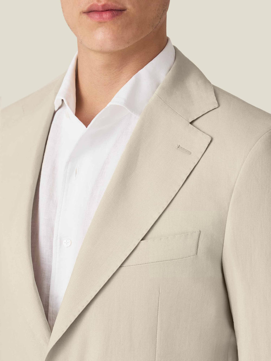 A close-up detail shot of the Sand Linen Blazer on a model, showcasing the notch lapel and fine linen texture.