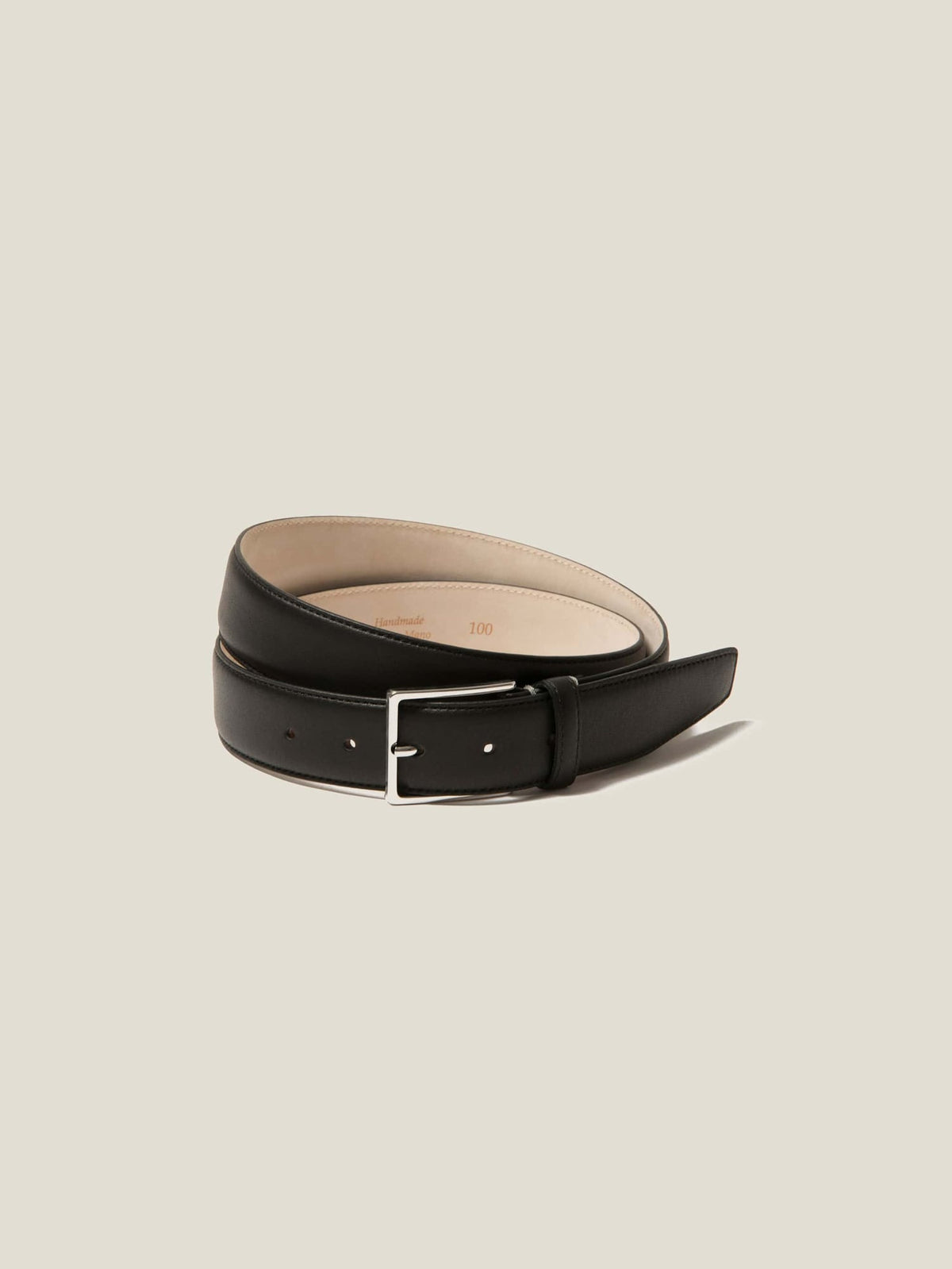 Studio shot of the Luca Faloni classic calf leather belt in black, coiled to display the silver buckle and smooth leather.