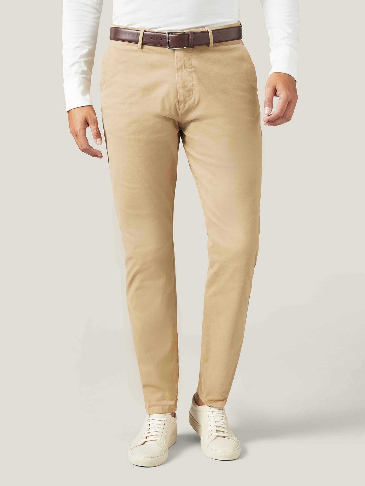 A model wears the Dark Brown Calf Leather Belt styled with beige chinos, a white long-sleeve shirt, and white sneakers.