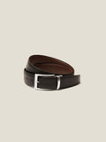 A reversible calf leather belt in black and brown, coiled with the black side facing out, featuring a silver-tone buckle.