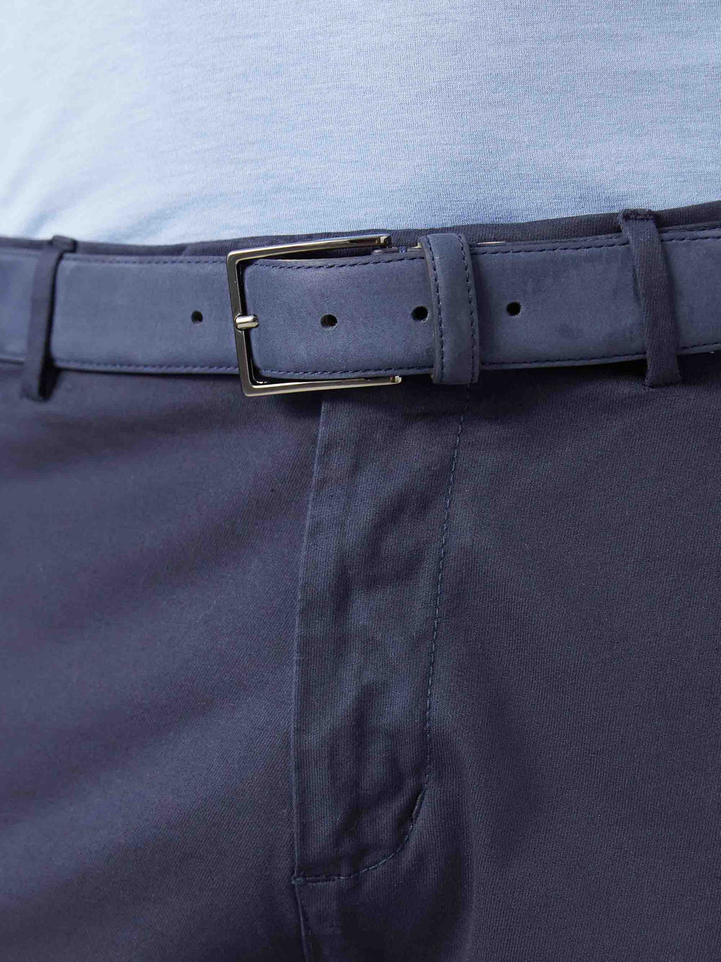 A close-up of the Luca Faloni Navy Blue Nubuck Belt, featuring a nickel buckle and worn with navy trousers.