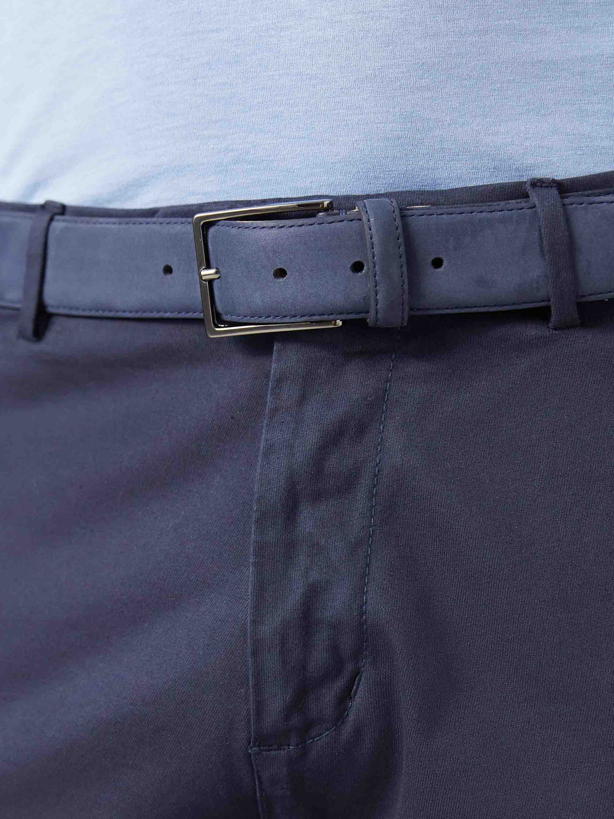 A close-up of the Luca Faloni Navy Blue Nubuck Belt, featuring a nickel buckle and worn with navy trousers.