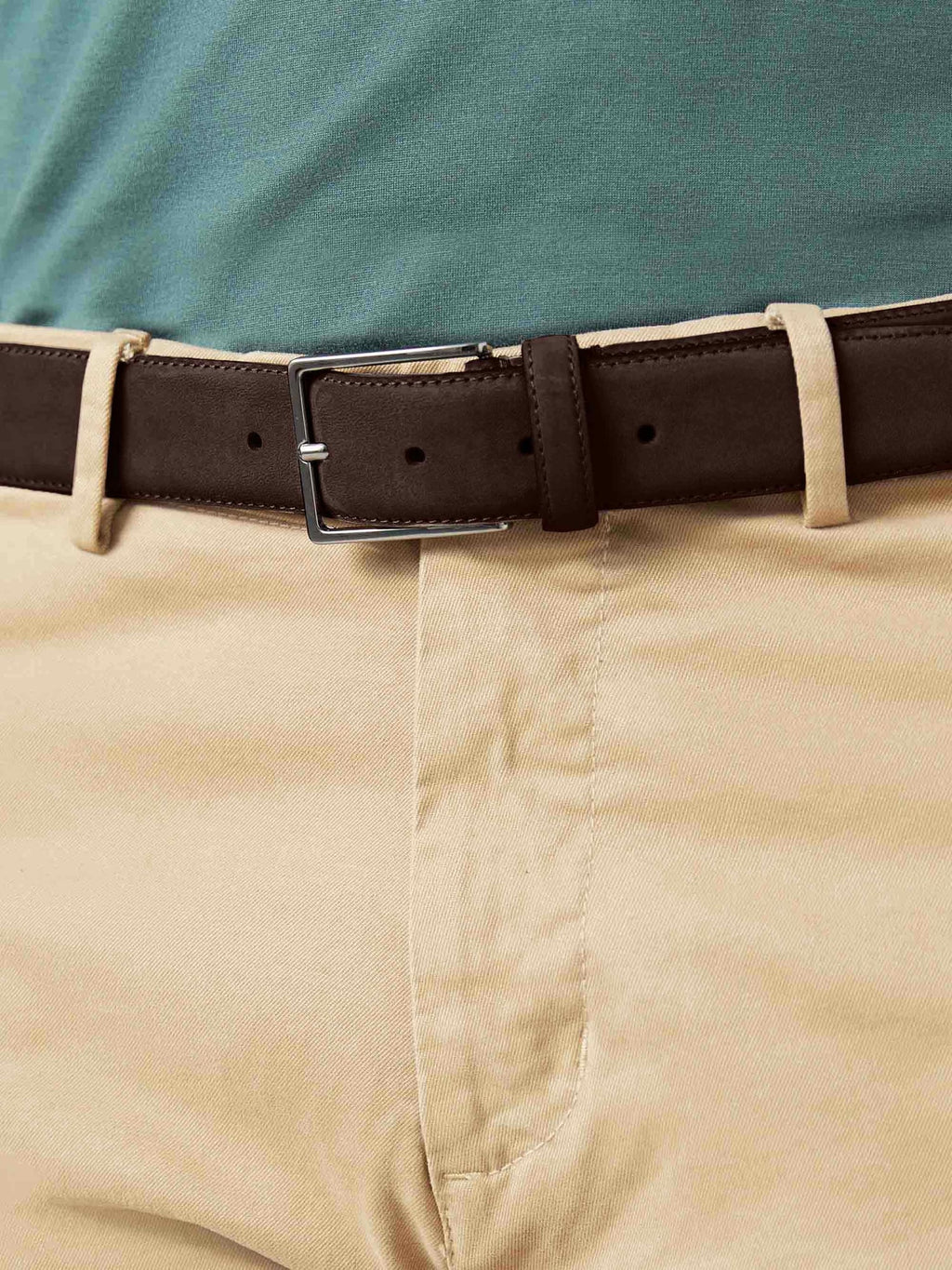 A close-up of the Luca Faloni Dark Brown Classic Suede Belt, showing its silver buckle and texture, worn with beige chinos.