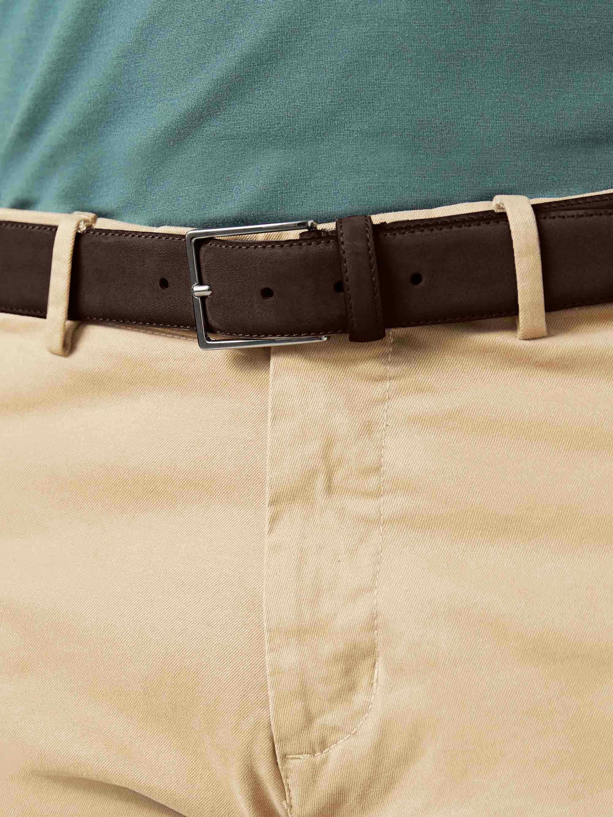 A close-up of the Luca Faloni Dark Brown Classic Suede Belt, showing its silver buckle and texture, worn with beige chinos.