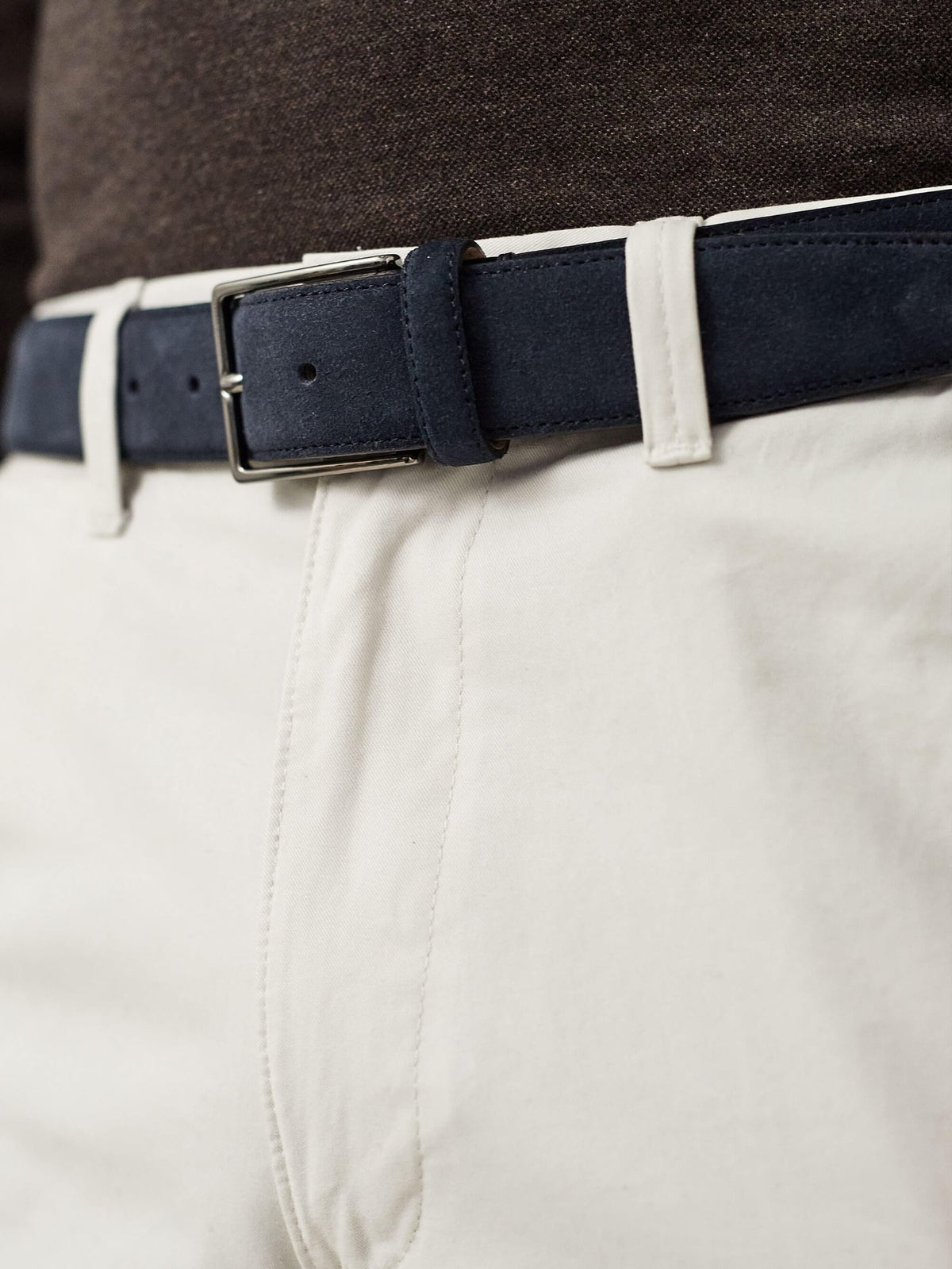 Close-up of the Luca Faloni Classic Suede Belt in navy blue, styled with off-white trousers and a dark top.