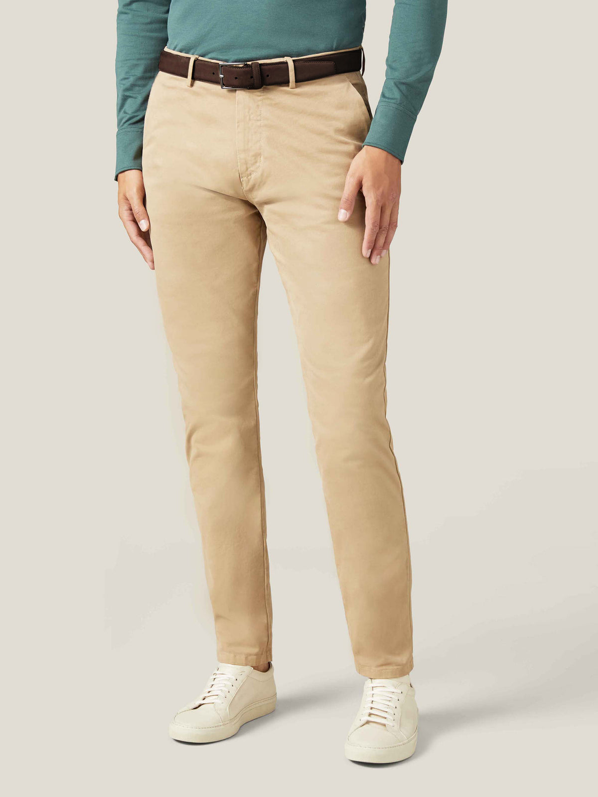 A model wears the Dark Brown Classic Suede Belt with beige chinos, a green long-sleeved top, and cream trainers.