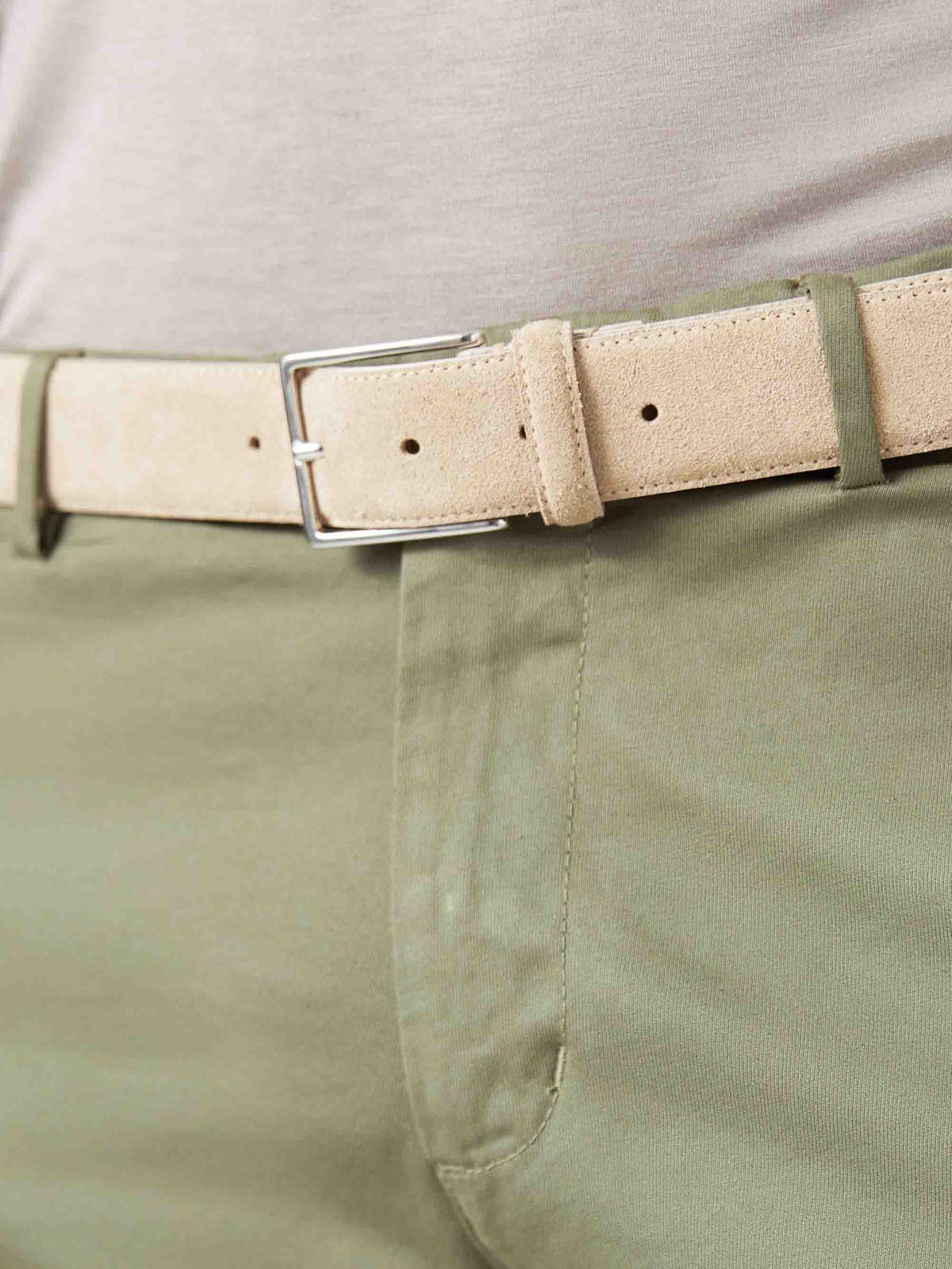 A close-up of the Luca Faloni Classic Suede Belt in Sand worn with a pair of green chinos.