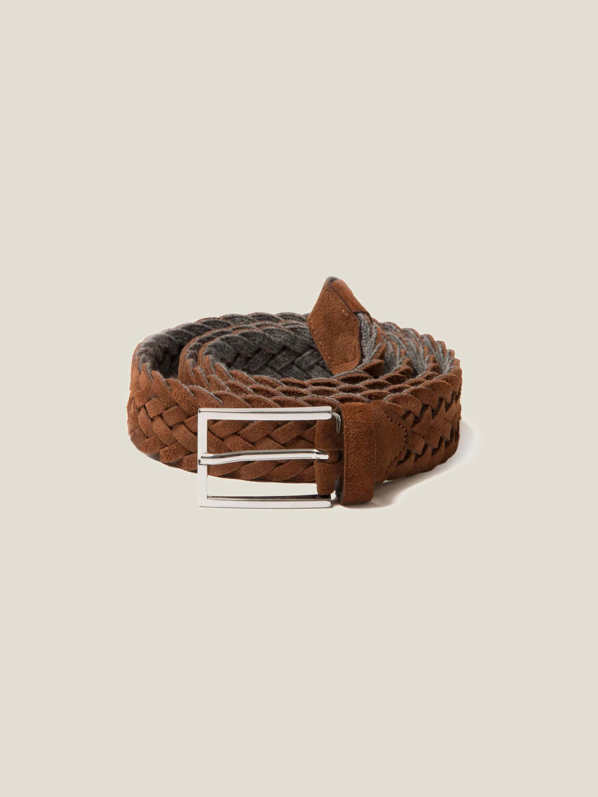 A coiled Luca Faloni woven belt in light brown suede leather, featuring its silver-finished buckle.