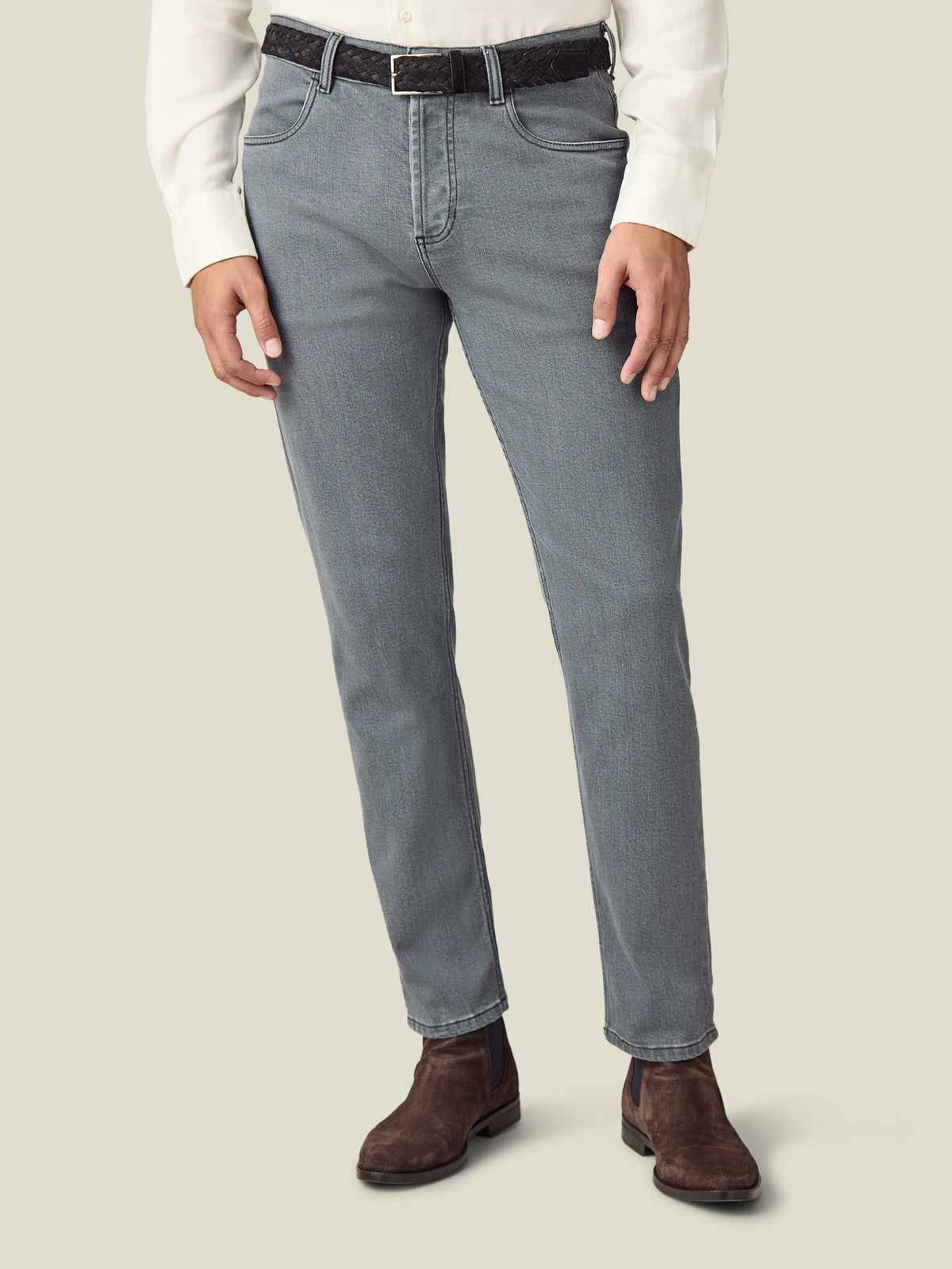 A model wears the Luca Faloni black Woven Belt, styled with grey jeans and a white shirt.