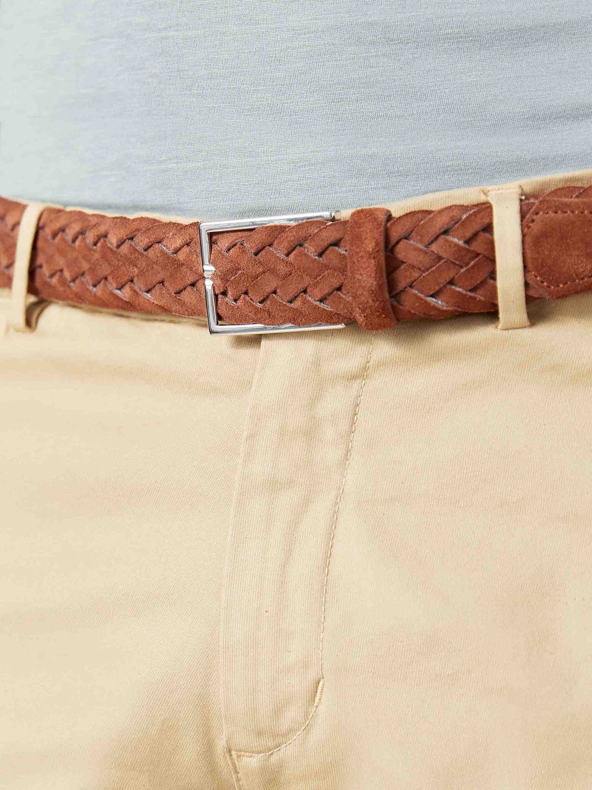 Close-up of the light brown Woven Suede Belt, showing its intricate weave and silver buckle on beige chinos.