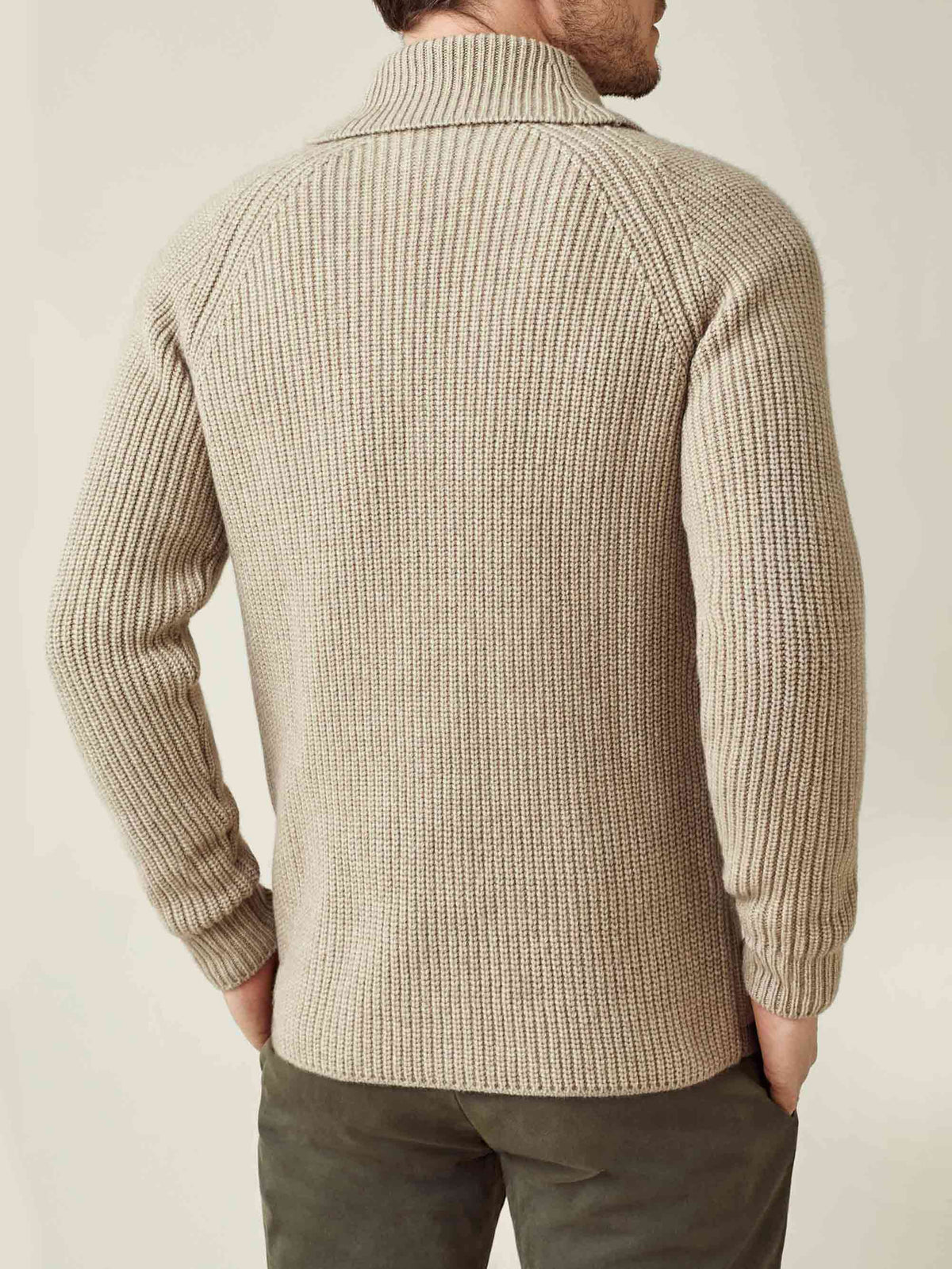 A man seen from behind wears the chunky knit cashmere cardigan in camel beige, showing its ribbed texture and shawl collar.