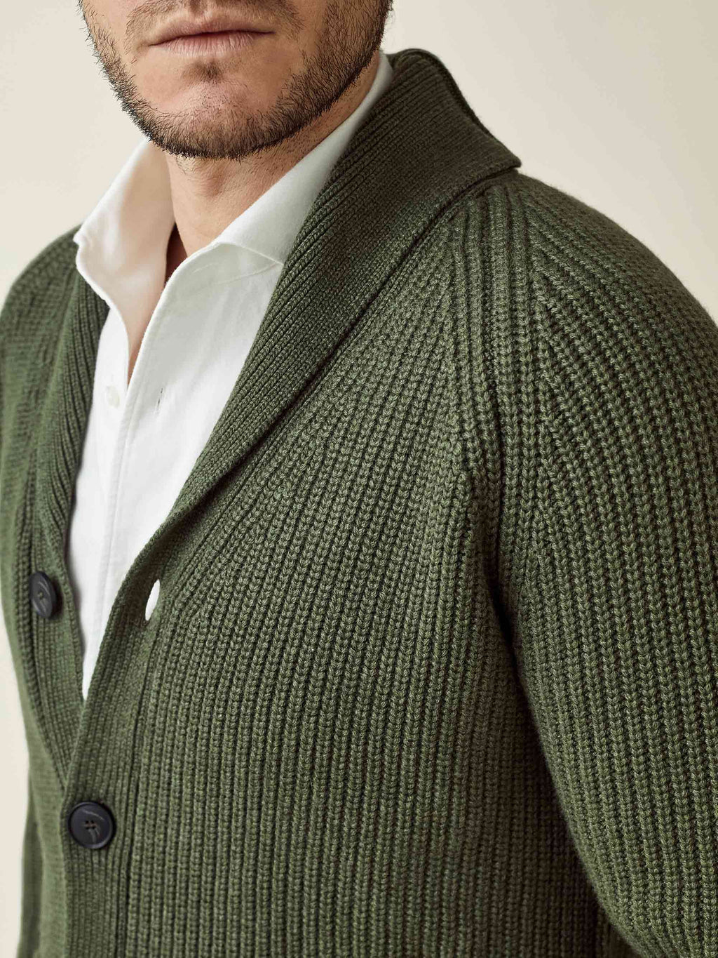 Detailed shot of a model wearing a hunting green chunky knit cardigan, highlighting the ribbed cashmere and shawl collar.