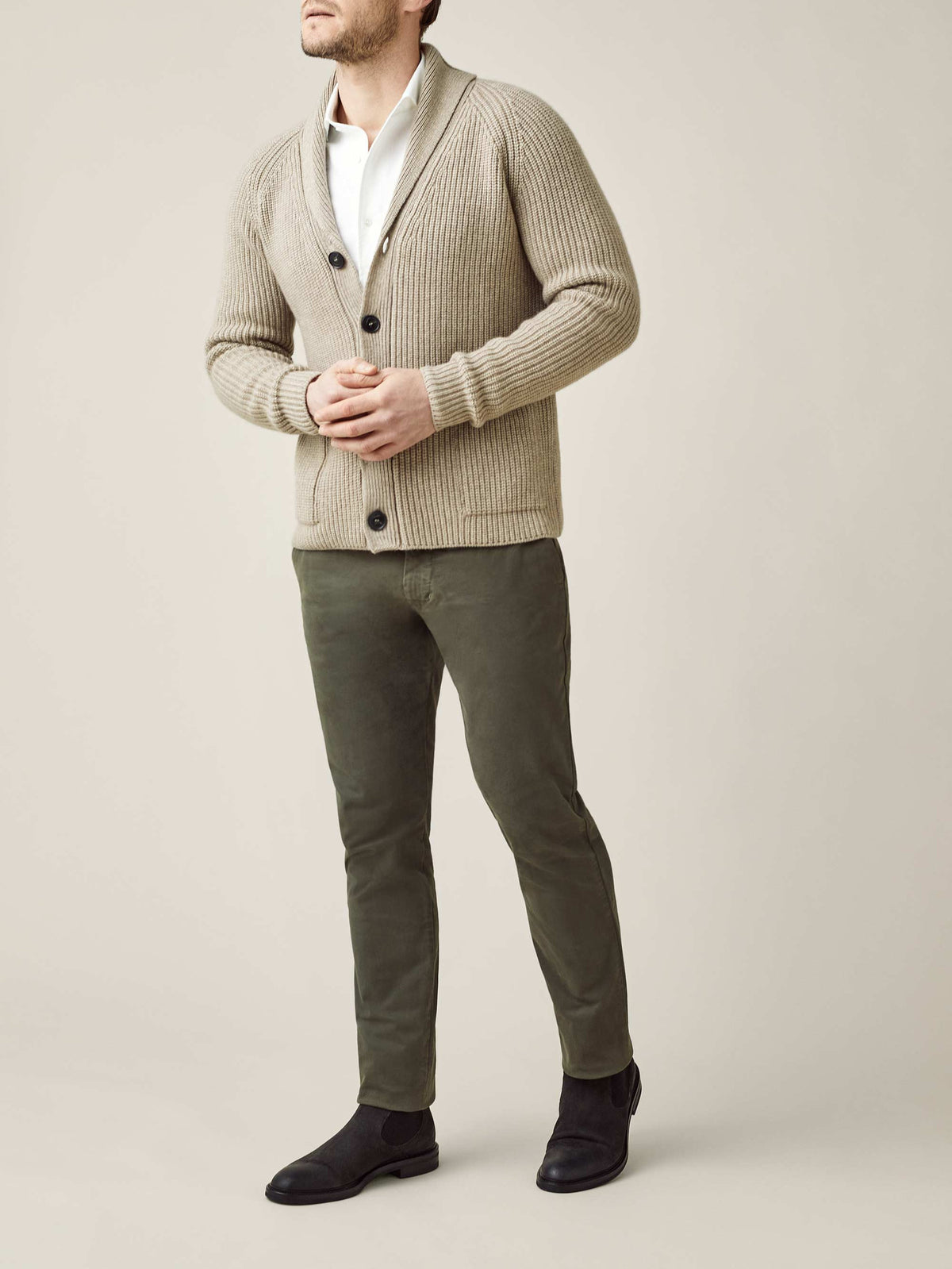 A model wears the Camel Beige Chunky Knit Cardigan with its shawl collar, styled with a white shirt and olive trousers.