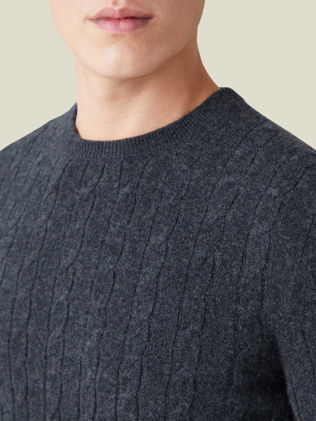 A man wearing the charcoal grey cashmere cable knit jumper, with a close-up on the crew neckline and textured knit detail.