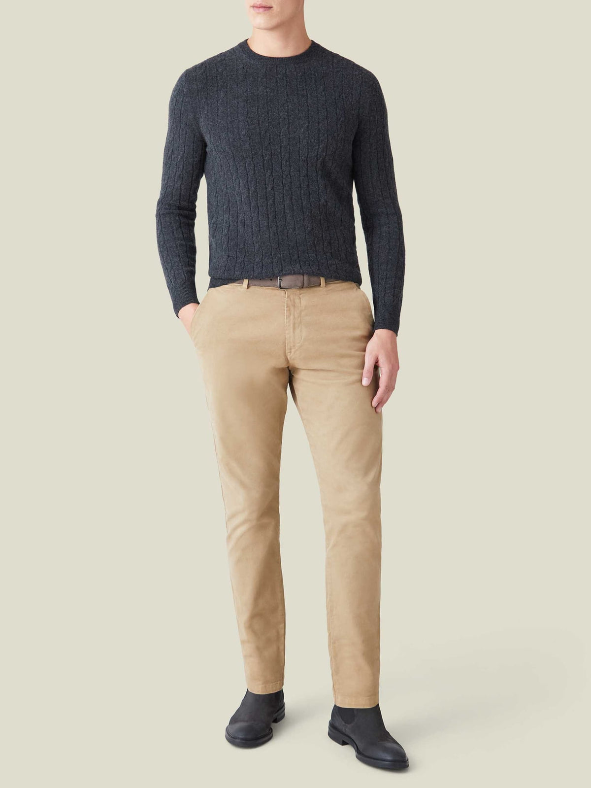 Front view of a model wearing the charcoal grey cashmere cable knit jumper, styled with beige chinos and black boots.