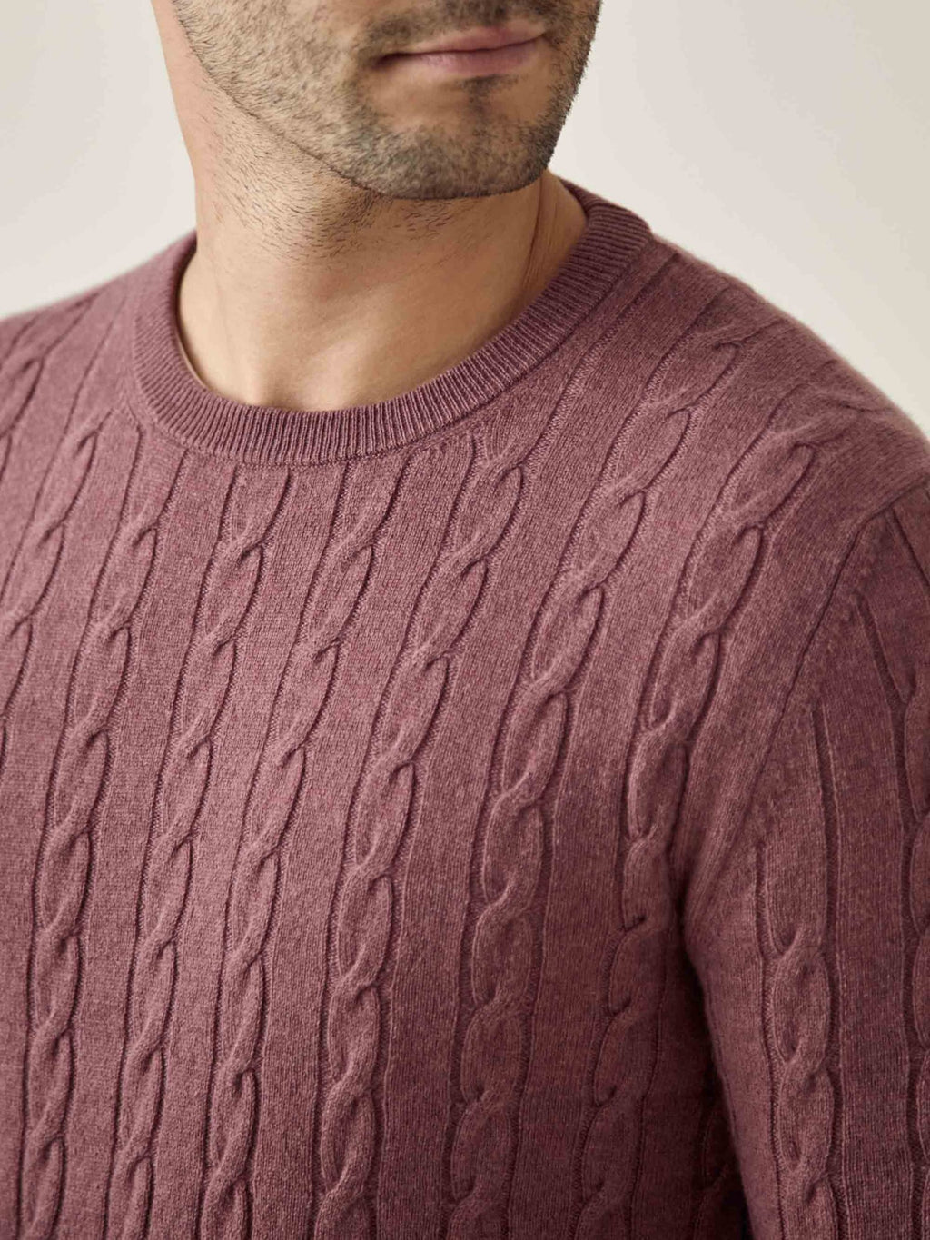 Close-up of a man wearing the Cable Knit jumper in Desert Rose, showing the detailed cashmere knit and crew neckline.