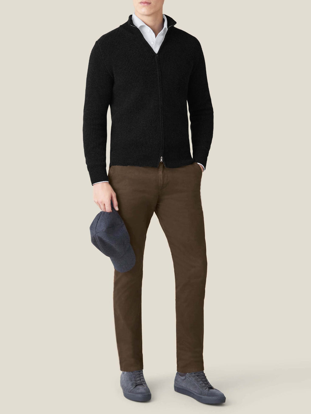 A model wears the Luca Faloni Black Chunky Knit Zip Cardigan with a white shirt, brown trousers, and dark grey sneakers.