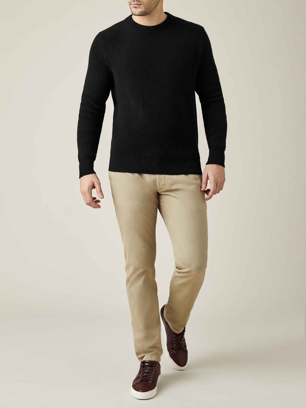 A front view of a model wearing the Black Chunky Knit Crew Neck with beige trousers and brown leather trainers.