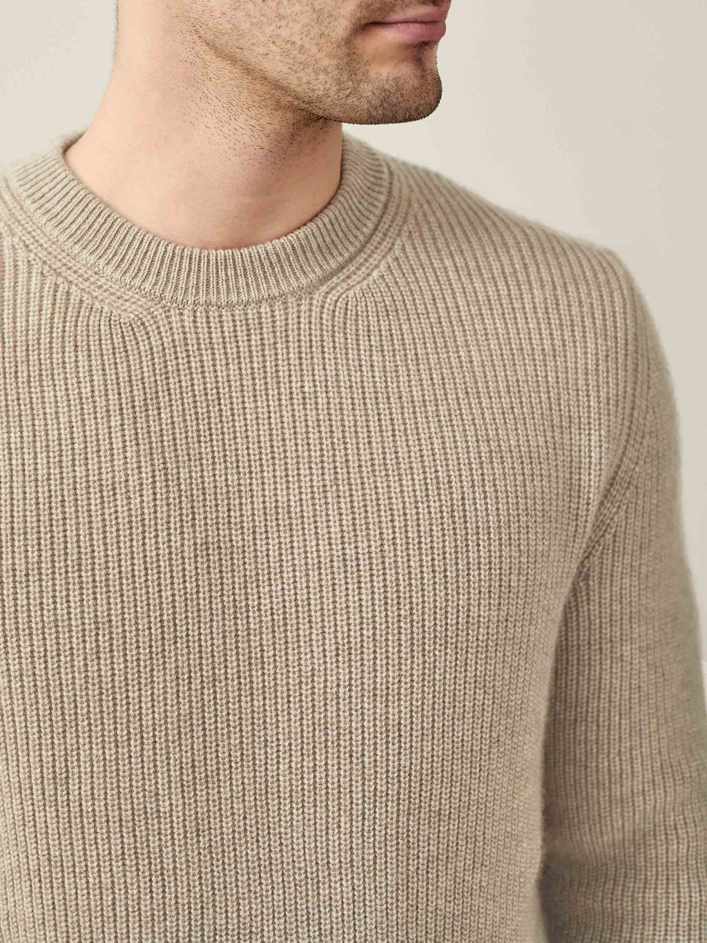 A man wears the Chunky Knit Crew Neck in Camel Beige, with a close-up showing the ribbed four-ply cashmere texture.