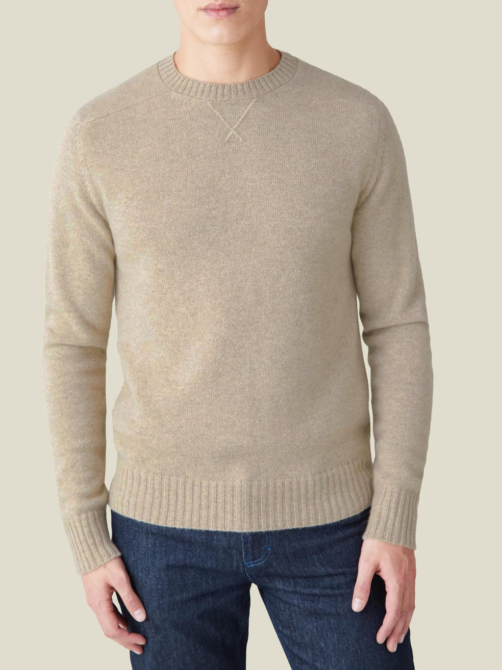 Front view of a model wearing the Country Crew Neck in Camel Beige cashmere, showcasing its cross-stitch collar detail.