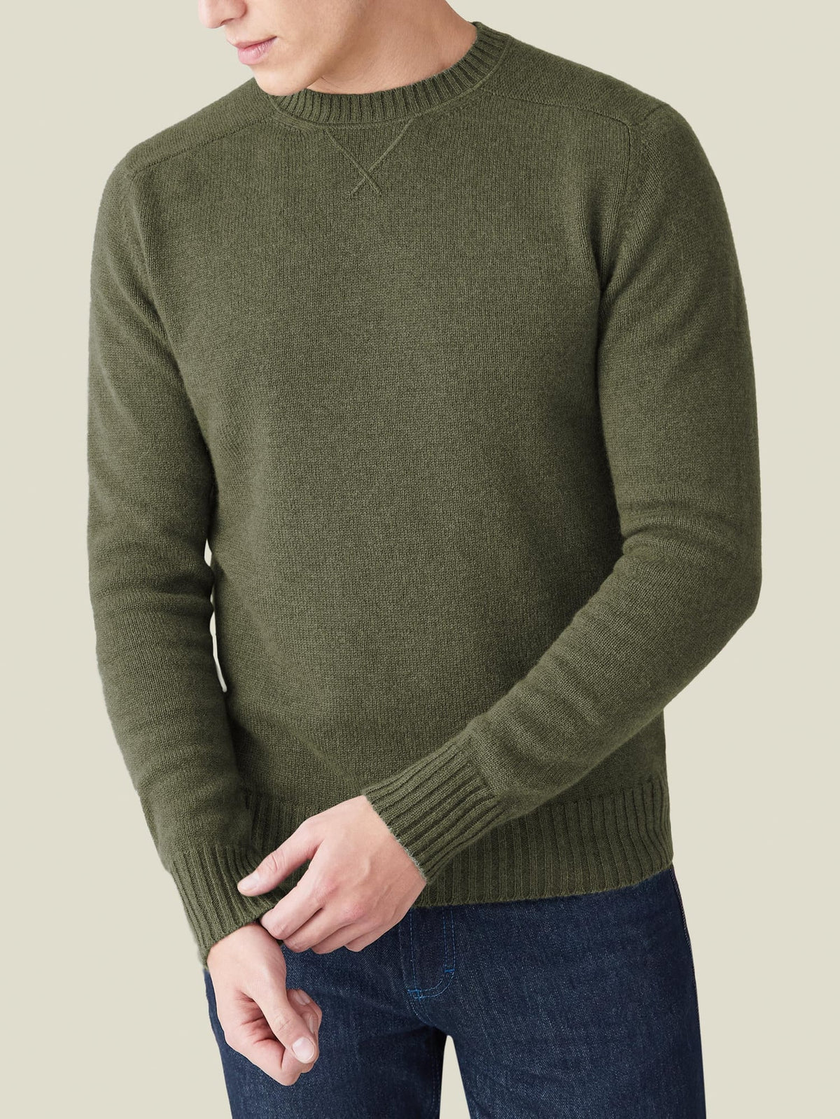 A man wears the four-ply cashmere Country Crew Neck in Hunting Green, showing its relaxed fit and cross-stitch collar.