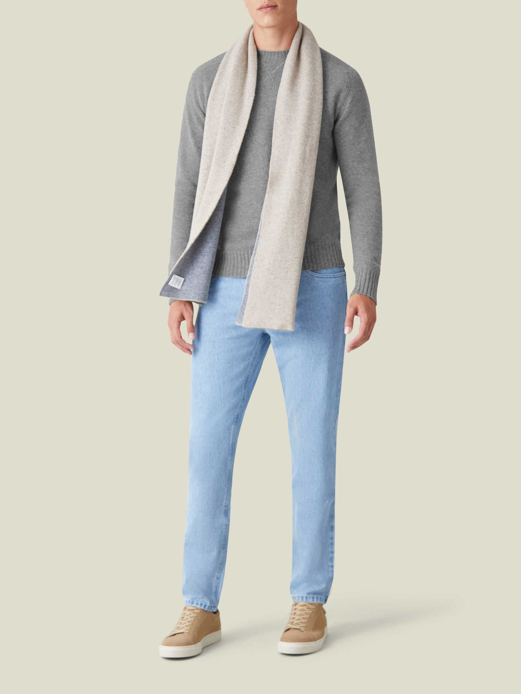 A model wears the Dolomiti Grey Country Crew Neck cashmere sweater, styled with light wash jeans and a two-tone scarf.
