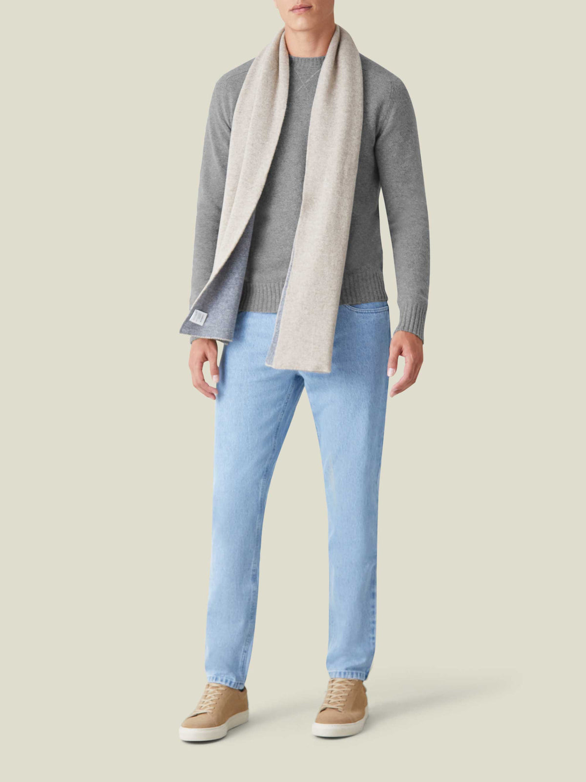 A model wears the Dolomiti Grey Country Crew Neck cashmere sweater, styled with light wash jeans and a two-tone scarf.