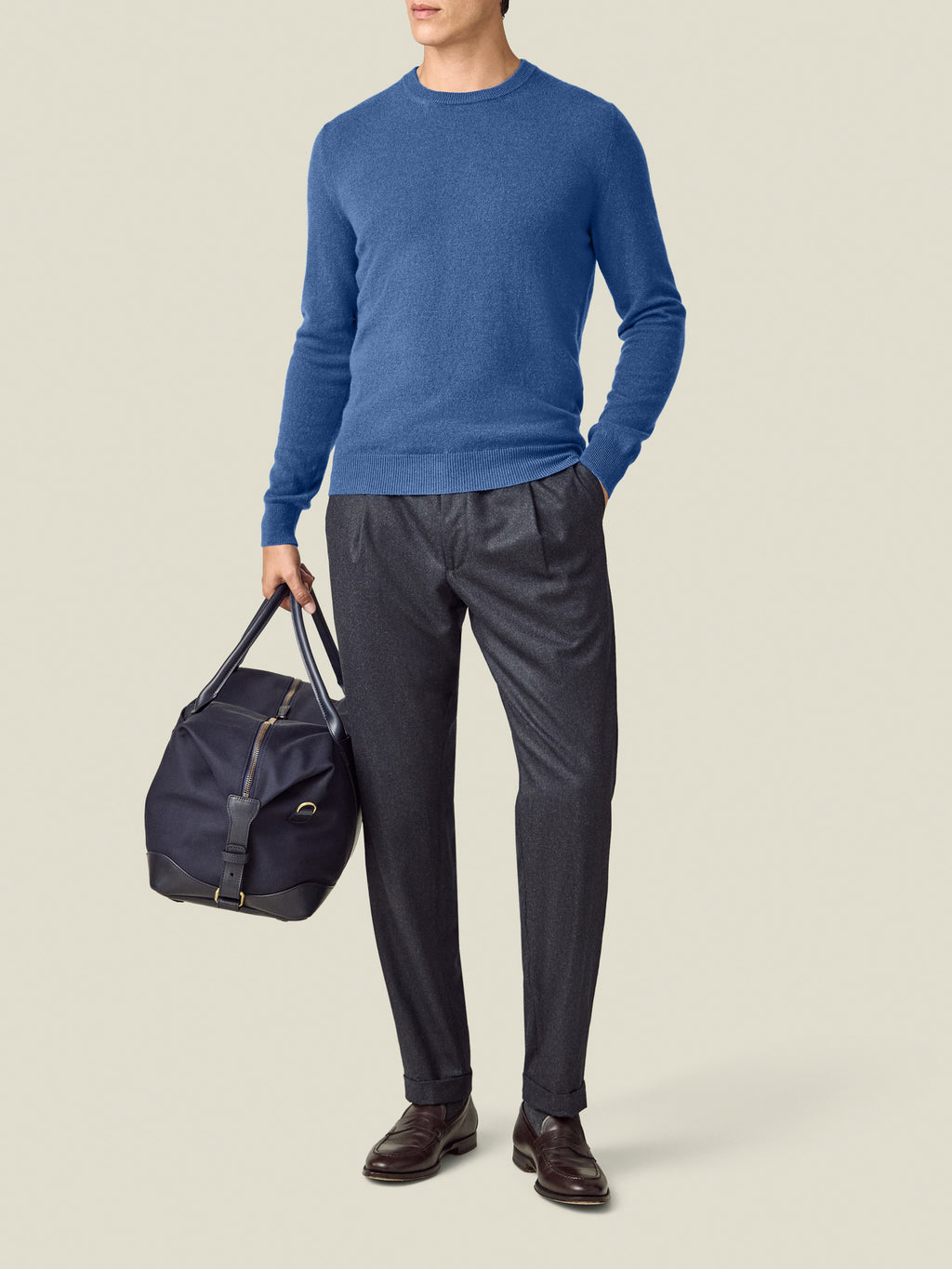 Front view of a model wearing the Luca Faloni Cobalt Blue Cashmere Crew Neck with grey trousers and a navy travel bag.