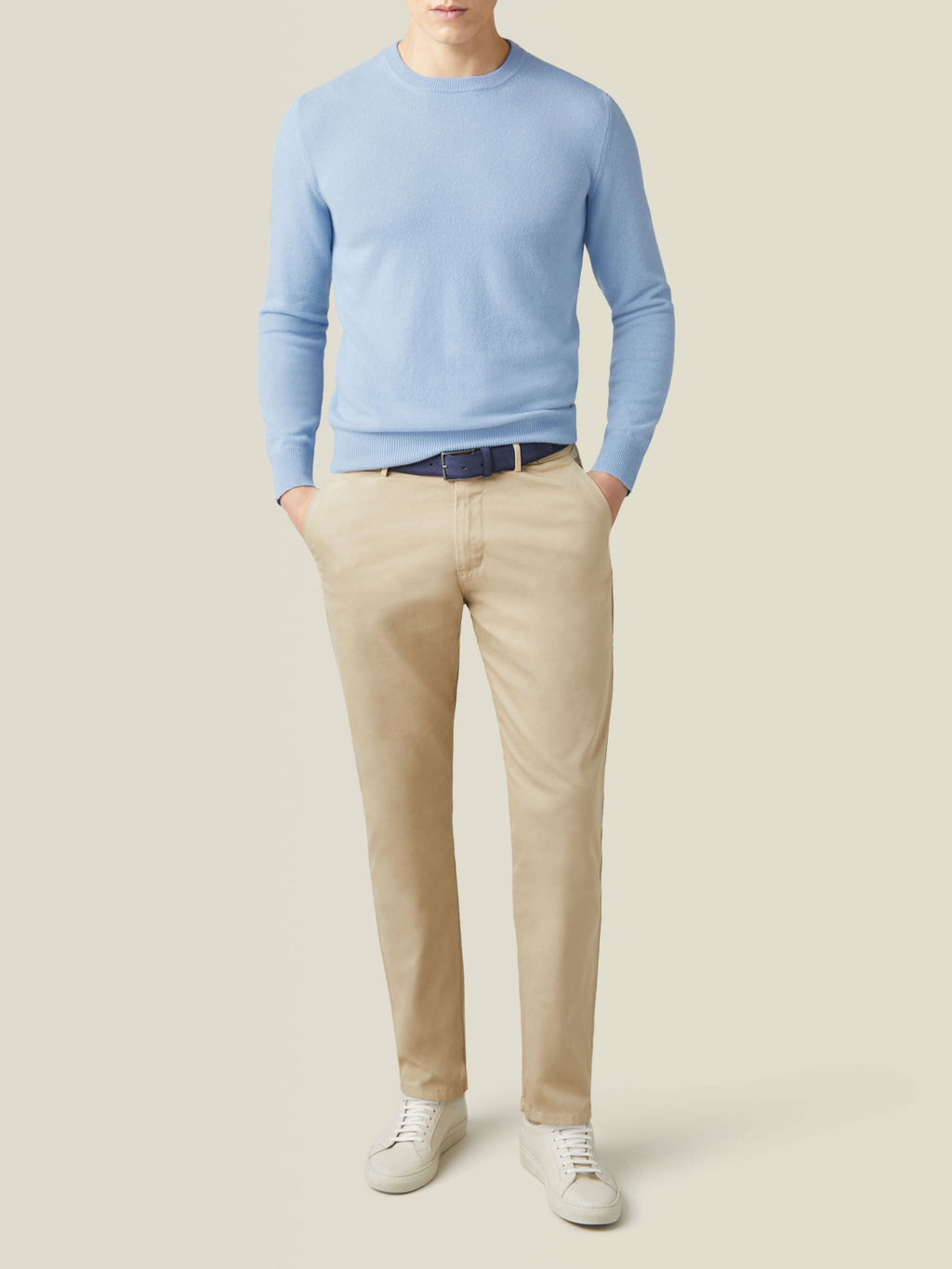 Full outfit view of a model wearing the sky blue cashmere crew neck with light brown chinos and white sneakers.